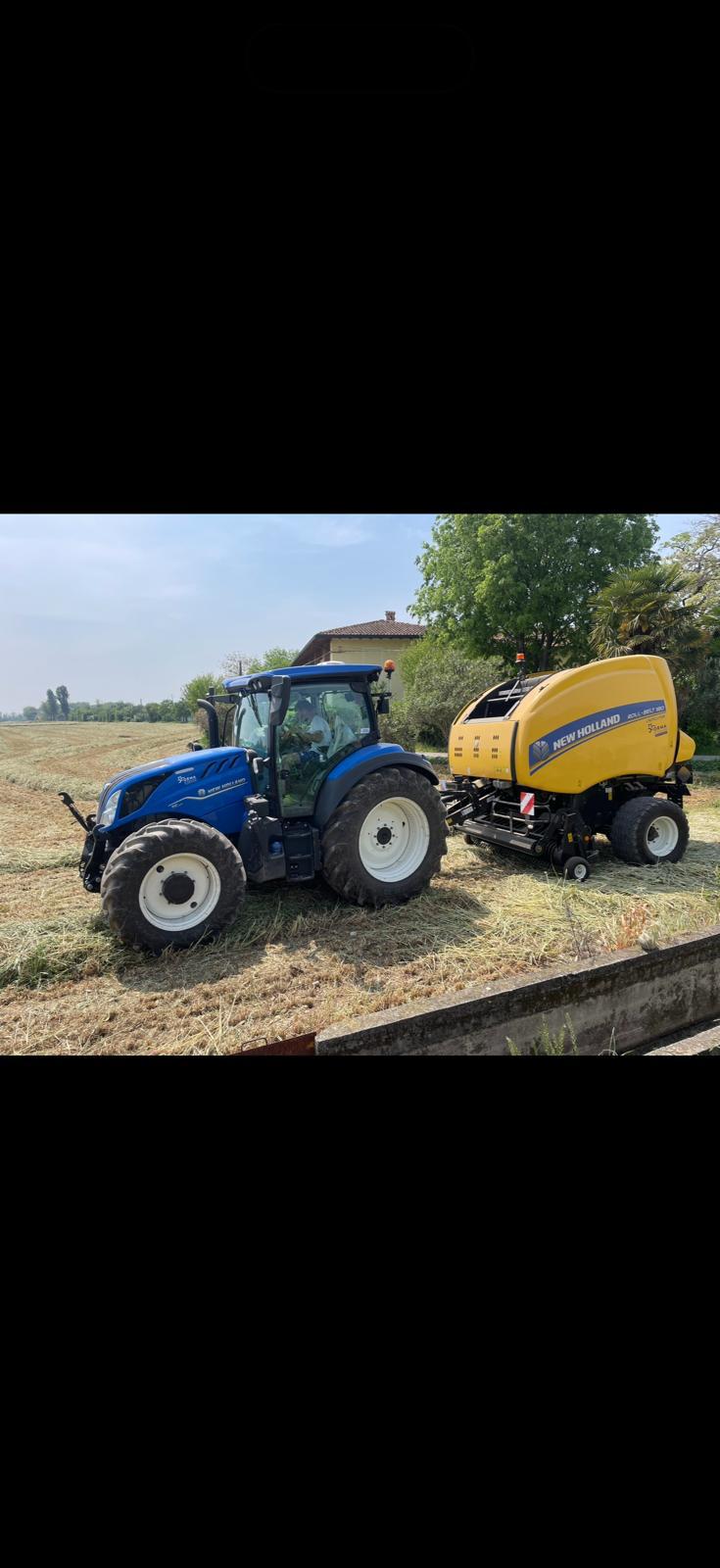 Trattore con rotopressa al lavoro in un campo di fieno