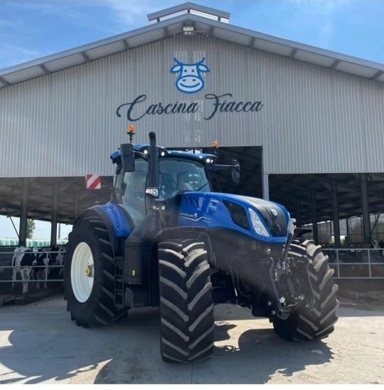Trattore New Holland davanti alla stalla con l'insegna Cascina Fiacca